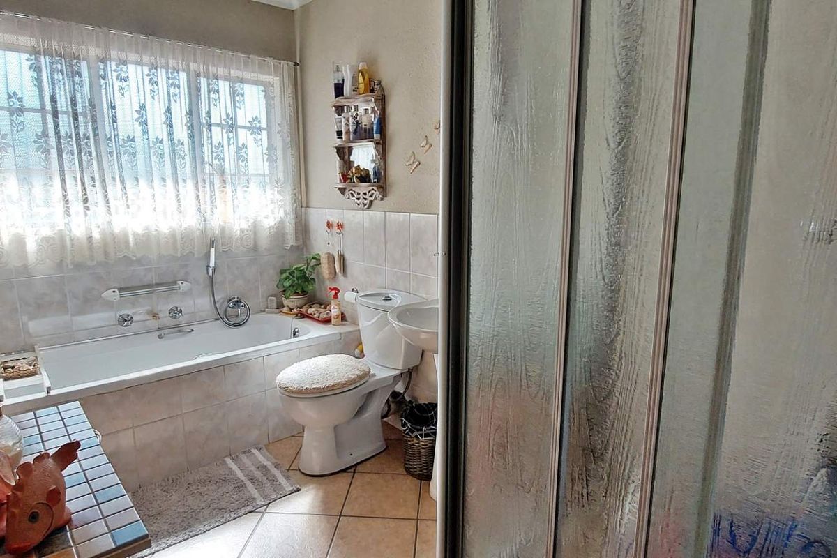 A functional bathroom featuring a built-in bathtub, pedestal sink, toilet, and a separate shower enclosure with textured glass doors.