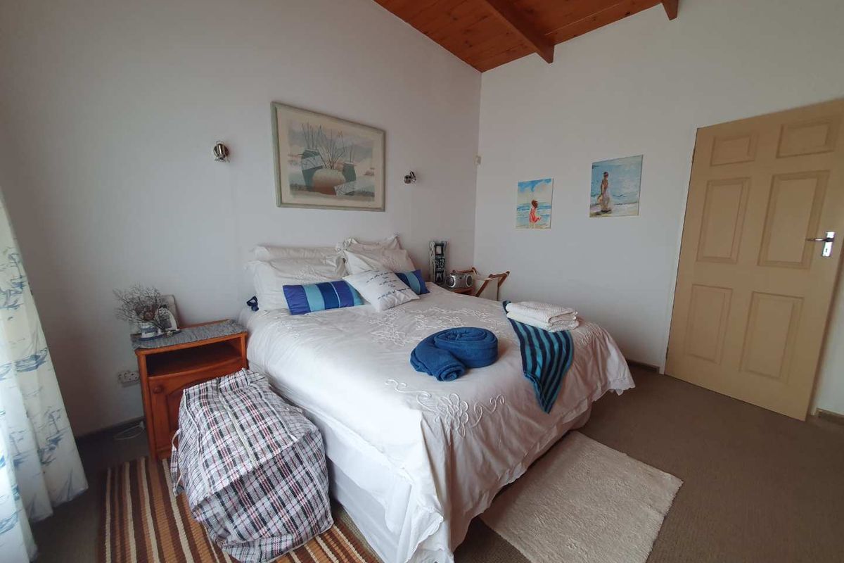 A bedroom featuring a vaulted timber ceiling, neutral walls, and carpeted flooring, providing a comfortable and functional sleeping space.
