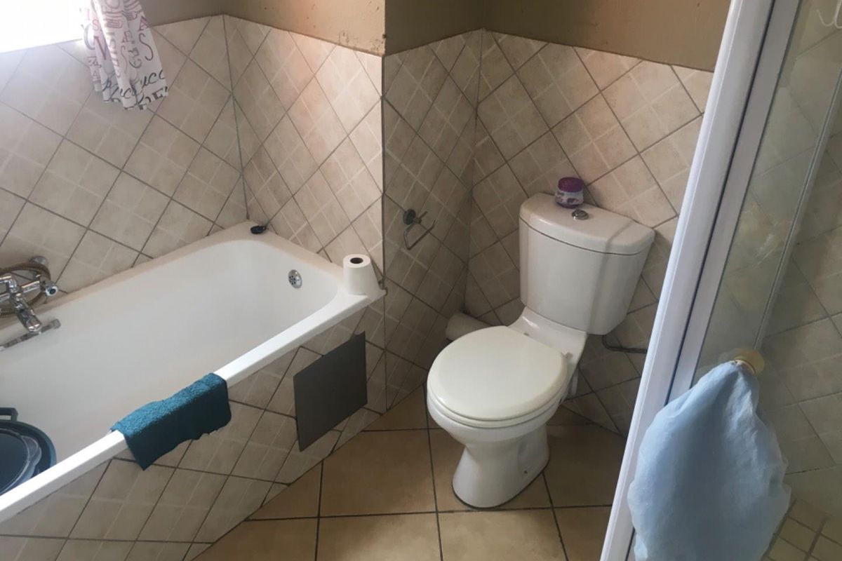 A functional bathroom featuring a bathtub, a standard toilet, and tiled wall and floor finishes.