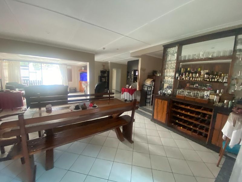 Spacious living area featuring a built-in bar with integrated wine storage and tiled flooring, offering a functional space for entertaining.