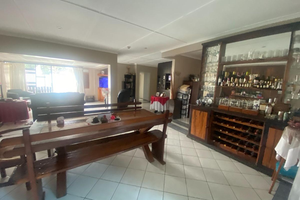 Spacious living area featuring a built-in bar with integrated wine storage and tiled flooring, offering a functional space for entertaining.