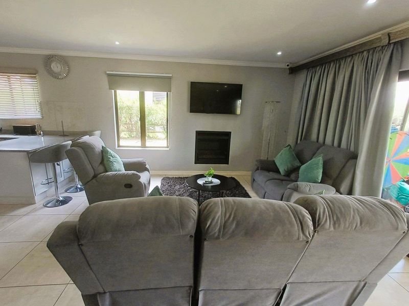 Open-plan living area featuring tiled floors, a built-in fireplace, and a breakfast bar connecting to the kitchen space.