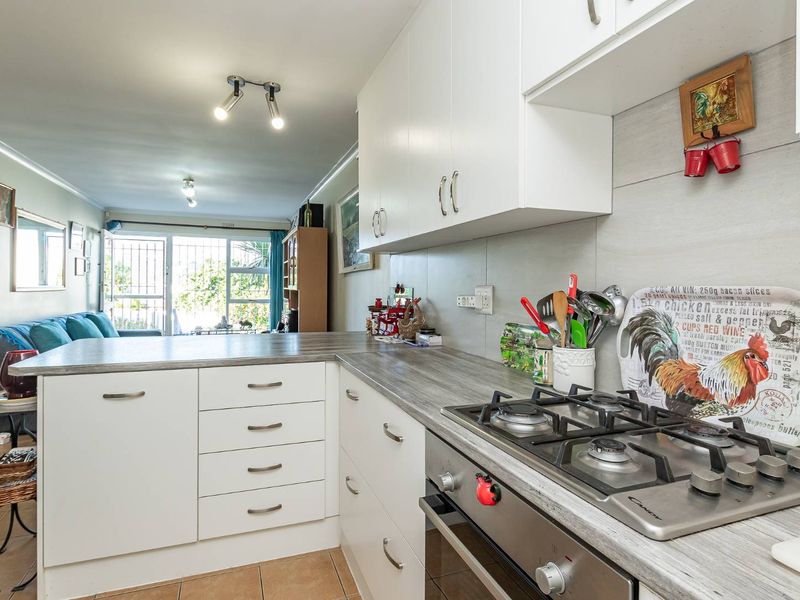 Open-plan kitchen and living area featuring white cabinetry, wood-look laminate countertops, gas hob, built-in oven, and direct access to an outdoor patio area.