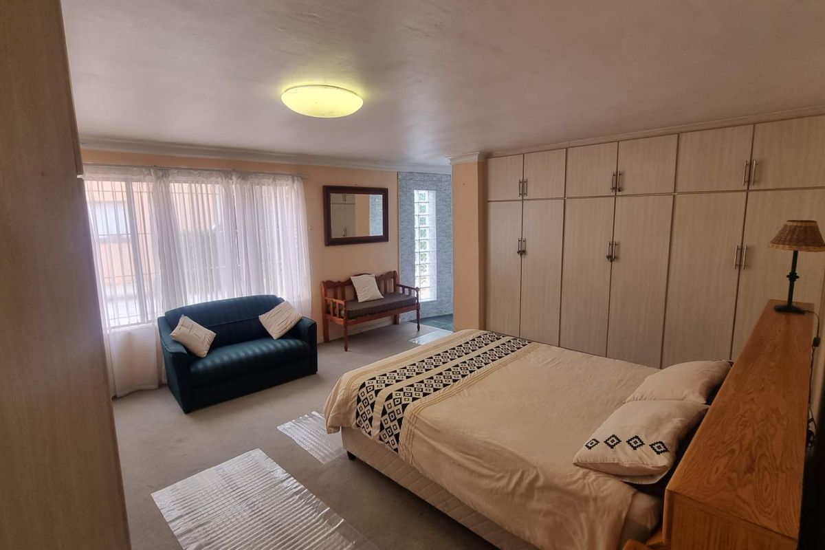 Spacious bedroom featuring extensive built-in cabinetry, neutral carpeting, and large windows allowing for ample natural light.