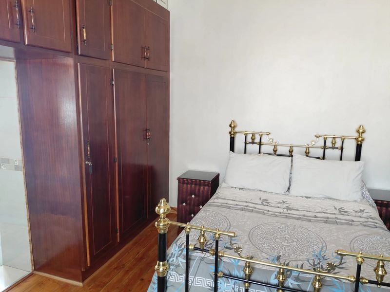 A bedroom featuring warm wooden flooring and extensive built-in wooden cabinetry for storage.