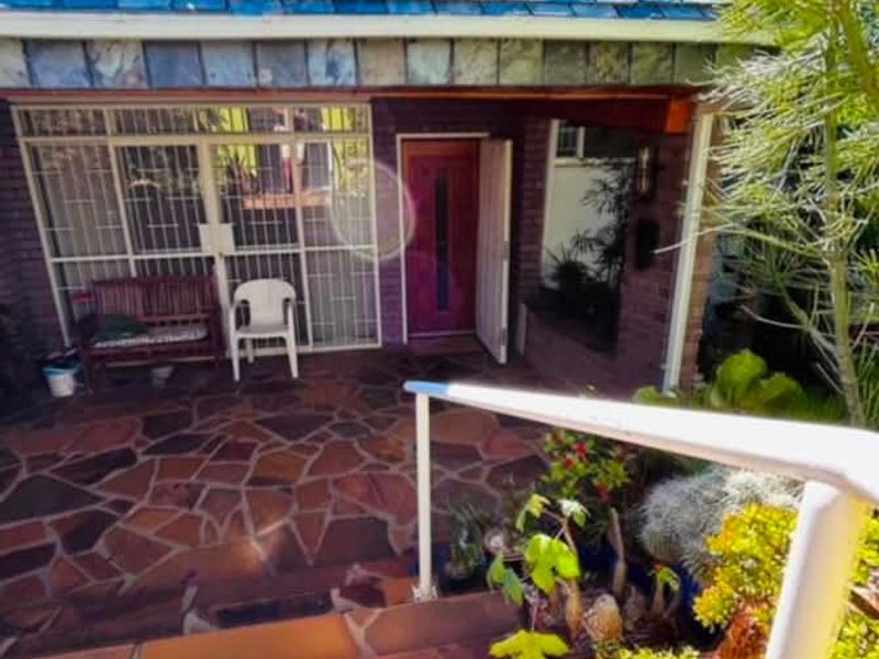 Front entrance area featuring a stone paved patio, slate roof, and secure gated access to the main doorway.