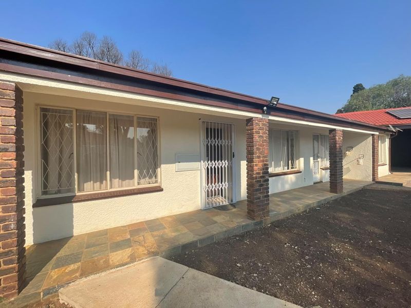Front elevation of a cluster home featuring a covered patio with brick pillars, security gates, and tiled flooring.
