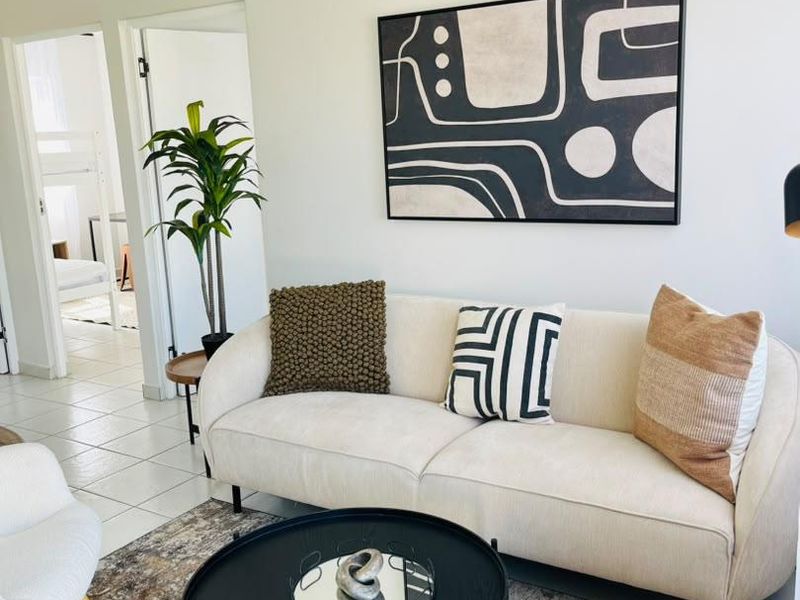 A bright and well-maintained living room featuring tiled flooring and a vaulted ceiling, providing a clean and inviting atmosphere.