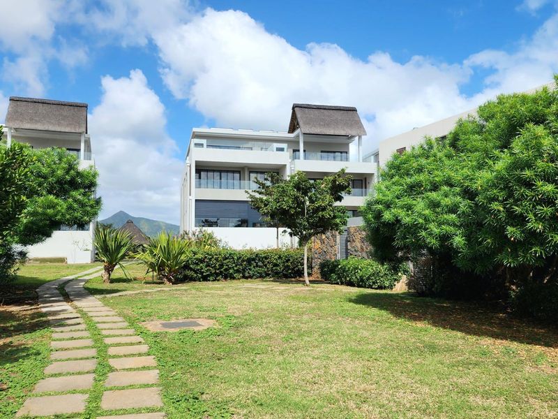 Rear view of the modern penthouse complex featuring landscaped gardens, paved walkways, and contemporary architecture with thatched roof elements.