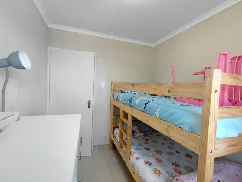 A standard bedroom featuring tiled flooring and neutral wall finishes, providing a functional space for a child's room.