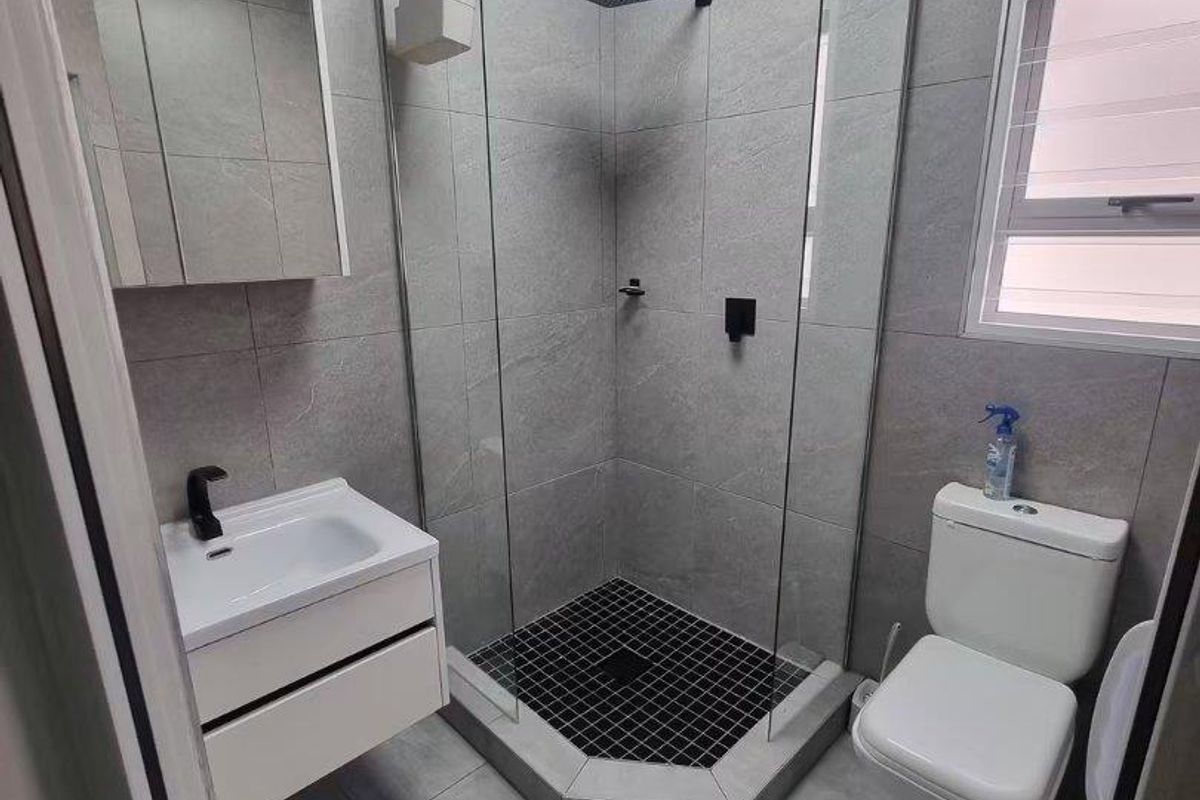 Modern bathroom featuring a walk-in shower with a rain shower head, wall-mounted vanity, and contemporary grey tiling throughout.