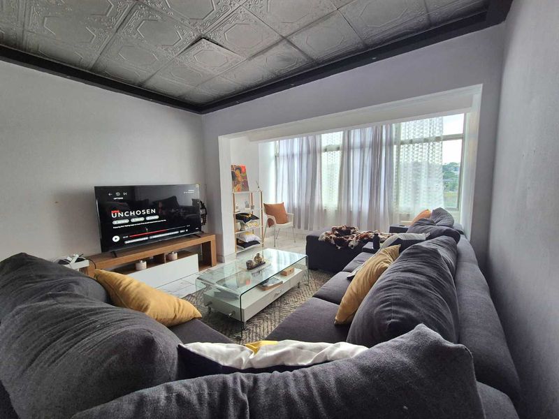 A comfortable living room featuring a unique decorative tin ceiling and a large window that provides ample natural light.