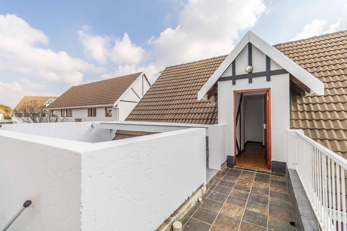 An elevated balcony area featuring tiled flooring, a white balustrade, and direct access to the interior through a timber door.