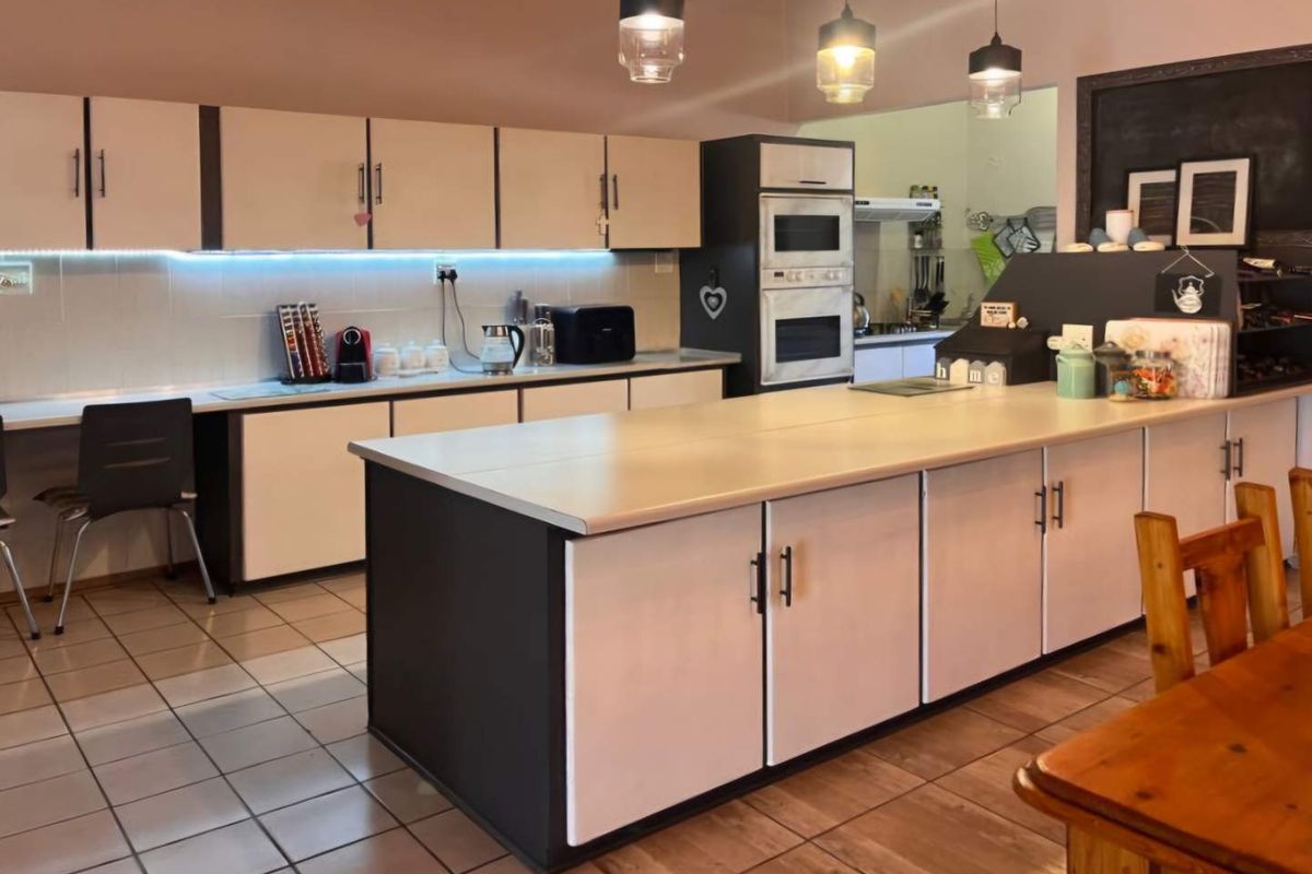 Spacious kitchen featuring a large central island, built-in cabinetry, integrated oven and microwave, and modern pendant lighting.