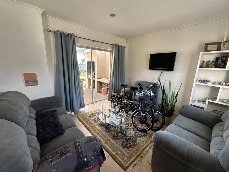 A comfortable living room featuring tiled flooring, recessed lighting, and a sliding glass door providing direct access to the outdoor patio area.