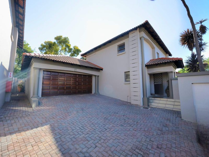 Front elevation of a two-story house featuring a paved driveway, double garage, and a covered entrance with architectural columns.
