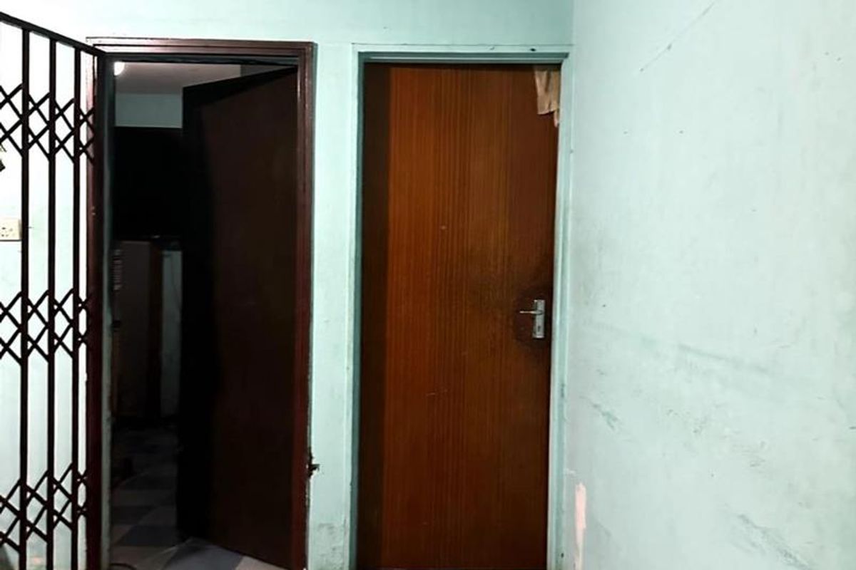 A vacant hallway featuring checkered floor tiles, a security gate, and internal doors, requiring cosmetic updates to the wall finishes.