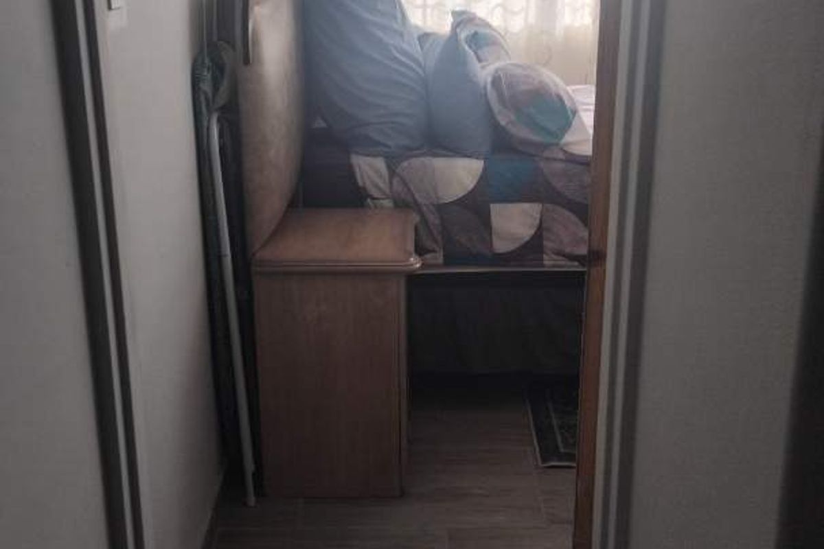 A view through a doorway into a bedroom featuring wood-look tile flooring and a window with curtains.