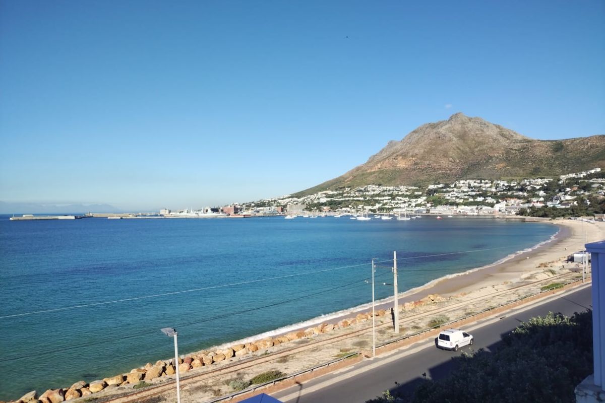 A scenic coastal view overlooking the bay, beach, and mountain range, capturing the expansive natural landscape surrounding the property.