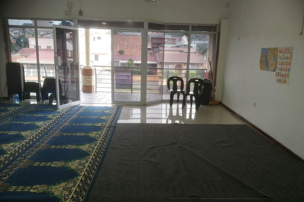 Open-plan interior space featuring large glass sliding doors leading to a balcony, with tiled flooring and neutral wall finishes.