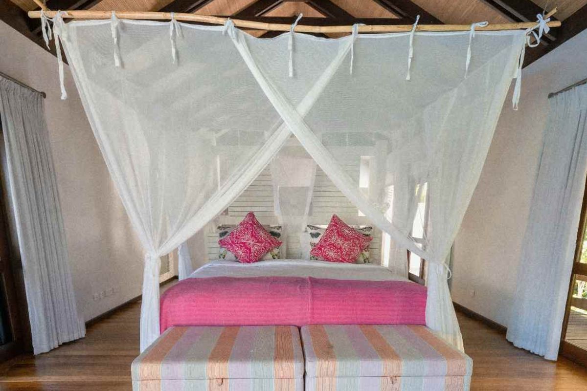 Spacious bedroom featuring high vaulted timber ceilings with exposed beams, hardwood flooring, and large windows allowing for ample natural light.