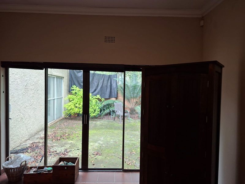 Living area featuring large sliding glass doors that provide direct access to a rear garden space with paved and landscaped areas.