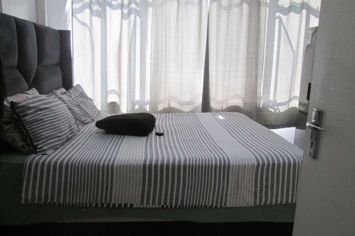A bedroom featuring a large window with curtains, providing natural light to the space.