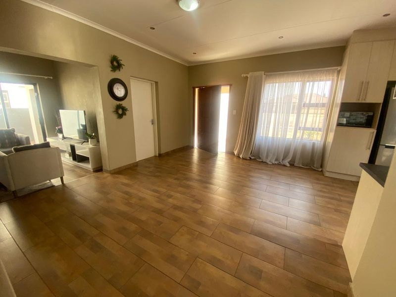 An open-plan living and kitchen area featuring wood-look tile flooring, recessed lighting, and neutral wall tones, creating a bright and functional living space.