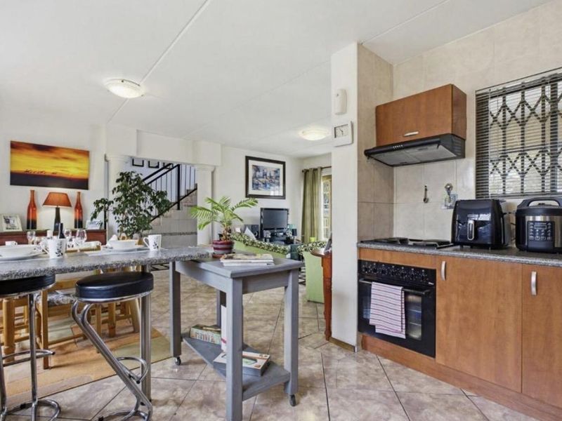 Open-plan living area featuring a functional kitchen with built-in oven, hob, extractor fan, and granite countertops, seamlessly flowing into the dining and lounge space.