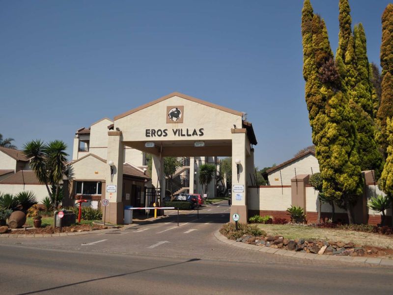 The main entrance to Eros Villas apartment complex, featuring a secure gated access point with a boom gate and perimeter walling.