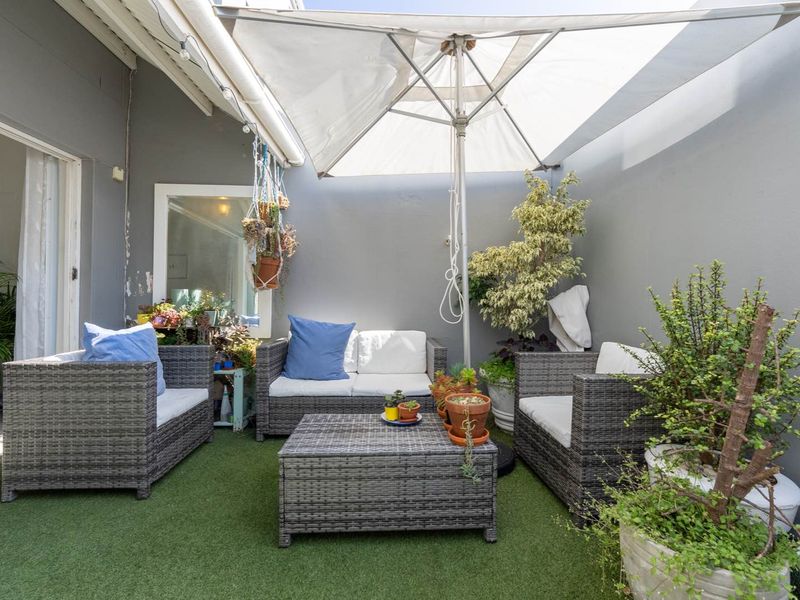 A private outdoor patio area featuring artificial turf flooring and enclosed by painted masonry walls, providing a cozy space for relaxation.
