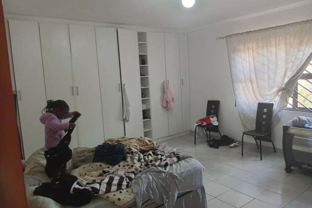 A bedroom featuring extensive floor-to-ceiling built-in cupboards and tiled flooring, providing ample storage space.