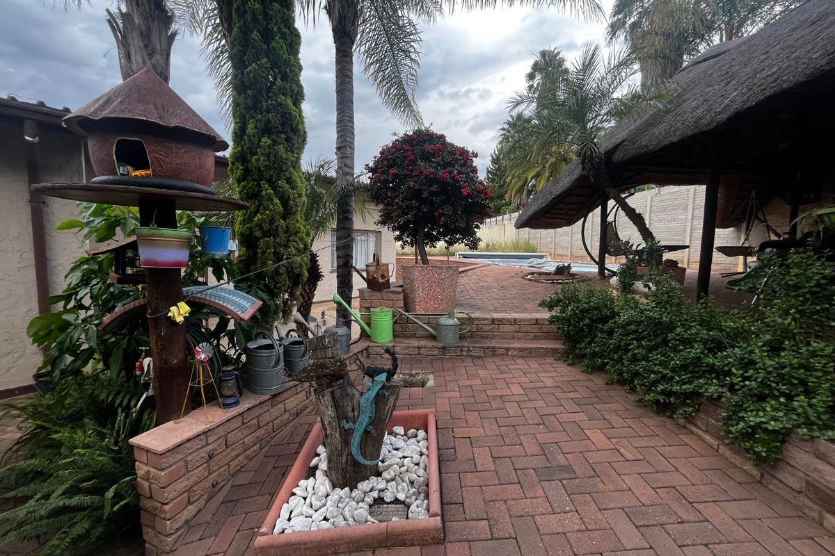 Rear garden area featuring brick paving, a thatched lapa, and a swimming pool, providing a functional outdoor entertainment space.