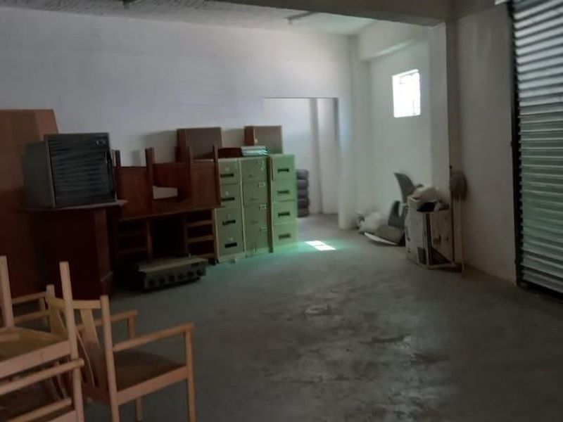 Spacious industrial utility area featuring a large roller shutter door and concrete flooring, suitable for storage or workshop use.