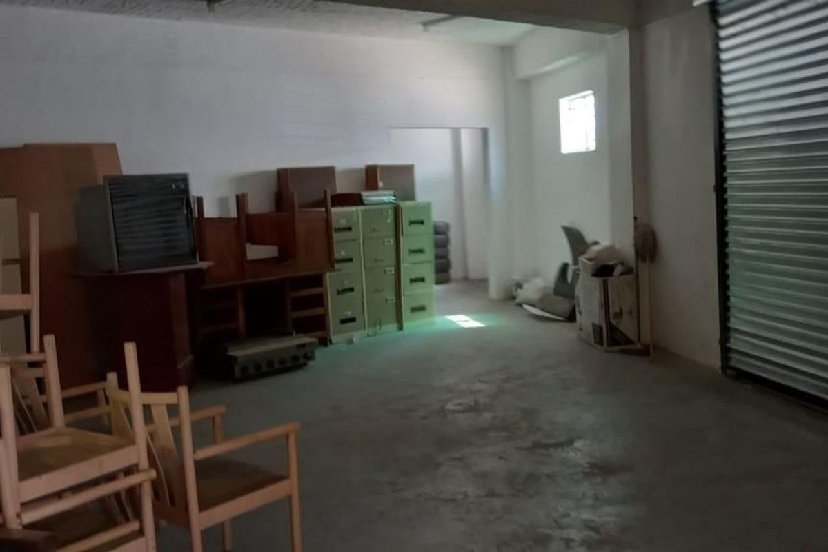 Spacious industrial utility area featuring a large roller shutter door and concrete flooring, suitable for storage or workshop use.