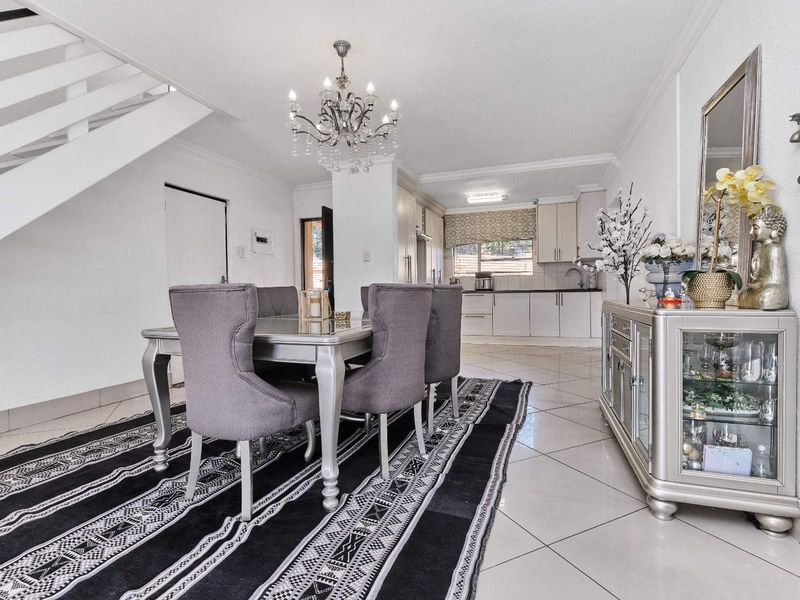 Open plan dining area featuring tiled flooring and a staircase, flowing into a functional kitchen with built-in cabinetry.
