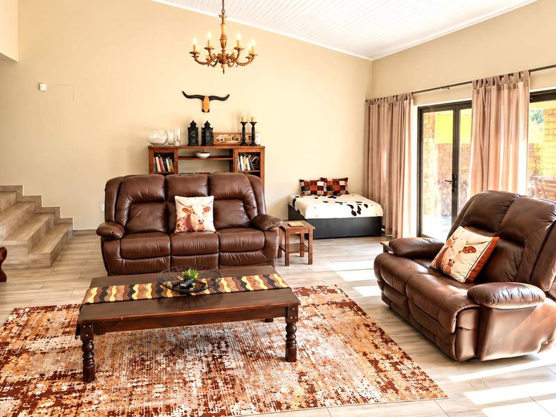Spacious living room featuring tiled flooring, vaulted ceilings, and large sliding glass doors providing natural light and access to the outdoor patio area.