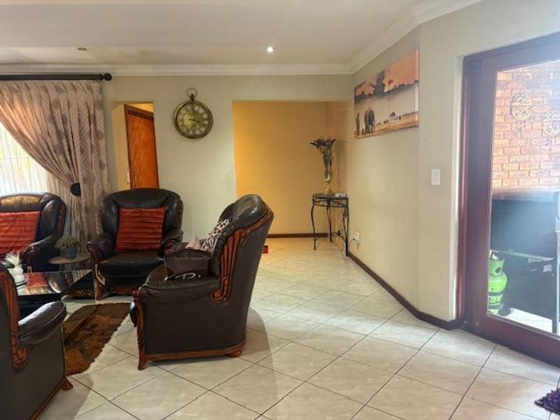 A living room area featuring tiled flooring, coved ceilings, and a timber door leading to an outdoor space.
