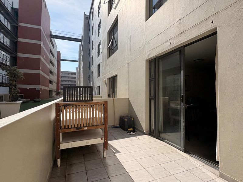 A functional apartment balcony featuring tiled flooring and a sliding glass door, providing an outdoor extension to the living space.