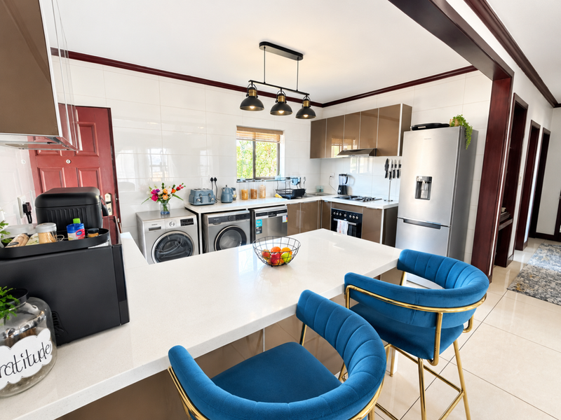 Modern kitchen featuring sleek cabinetry, quartz countertops, integrated appliances, and a breakfast bar, finished with high-quality tiling and contemporary pendant lighting.