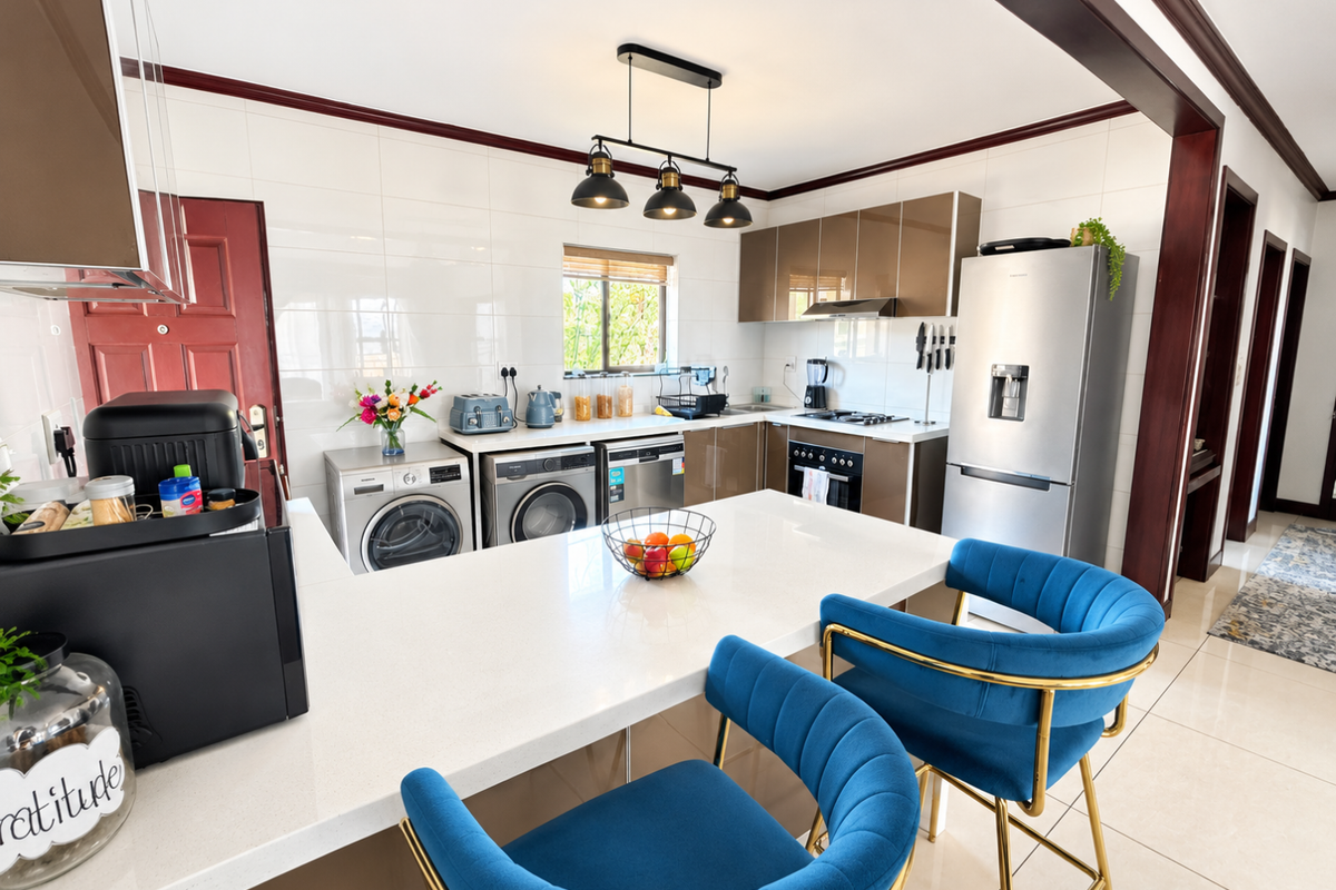 Modern kitchen featuring sleek cabinetry, quartz countertops, integrated appliances, and a breakfast bar, finished with high-quality tiling and contemporary pendant lighting.