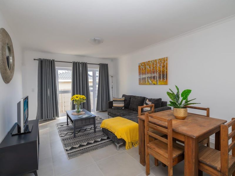 An open-plan living and dining area featuring neutral tiled flooring and a sliding glass door providing access to the exterior.