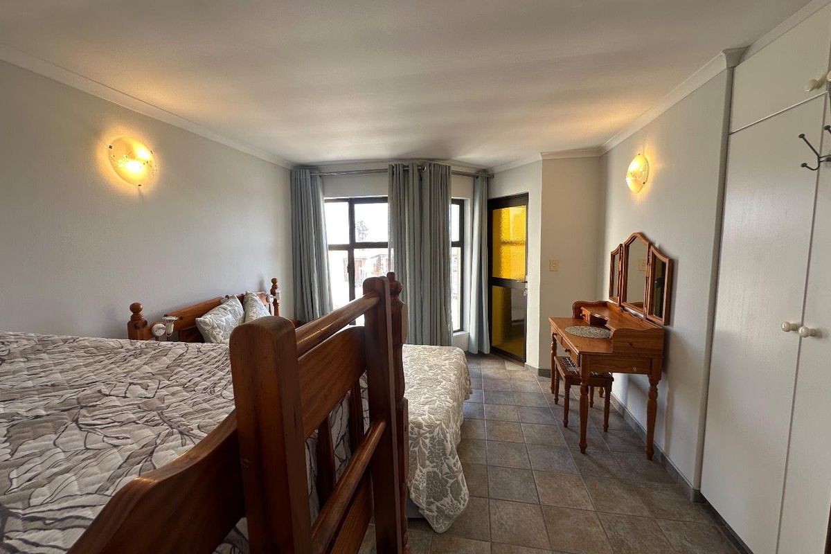 A spacious bedroom featuring tiled flooring, built-in cupboards, and direct access to an outdoor balcony area.
