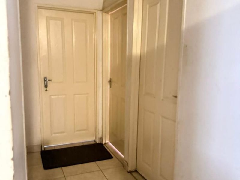 A functional hallway featuring tiled flooring and multiple panelled interior doors, requiring minor cosmetic updates to the wall finishes.