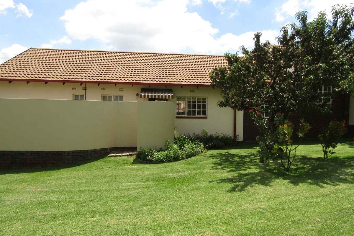 A view of the rear exterior of the retirement unit, featuring a tiled roof, plastered walls, and a well-maintained private garden area.