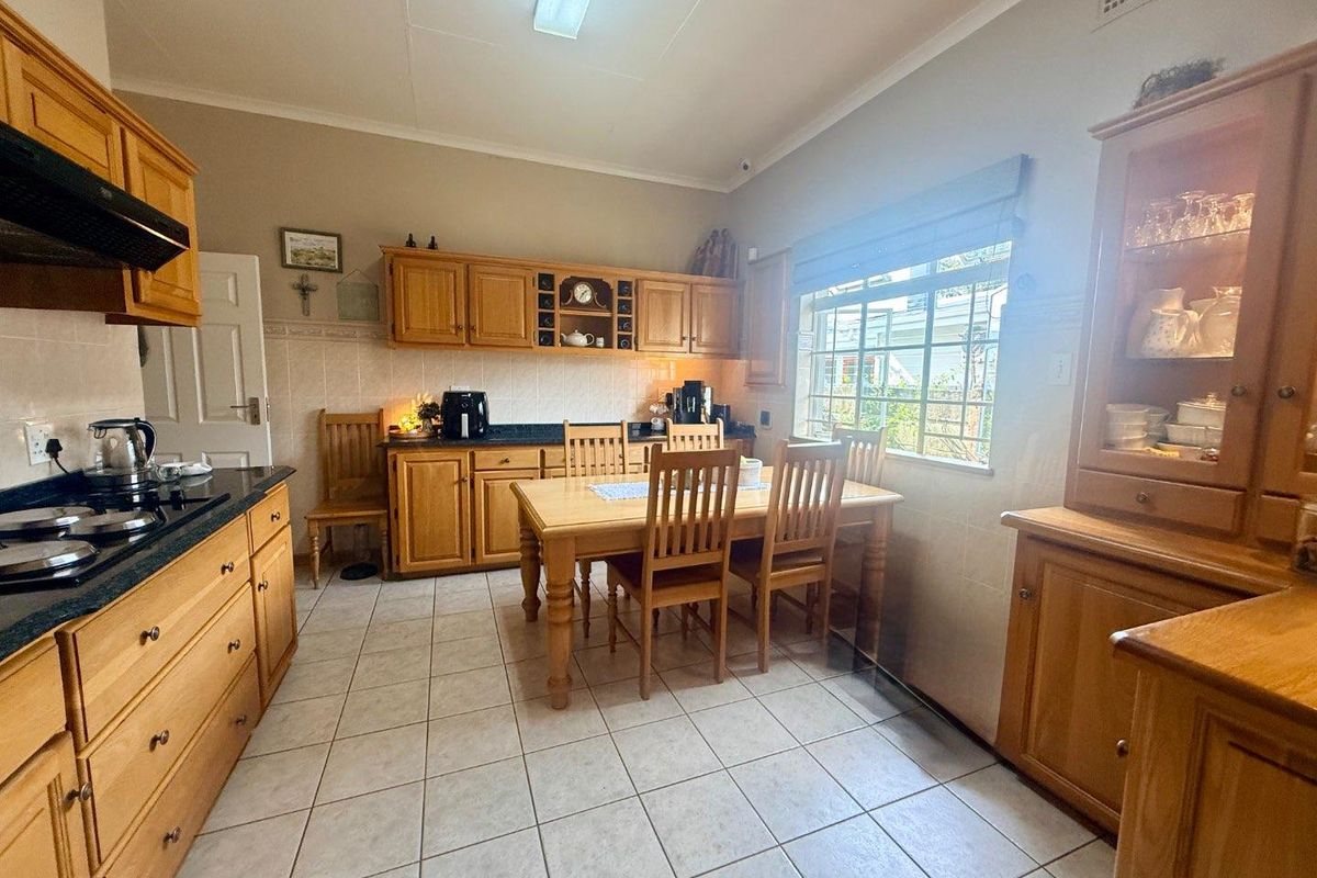 A traditional kitchen featuring wooden cabinetry, tiled flooring, a built-in gas hob, and an integrated extractor fan with an adjacent dining area.