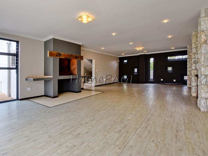 Spacious open-plan living area featuring a built-in fireplace, stone accent wall, and modern laminate flooring with recessed lighting throughout.