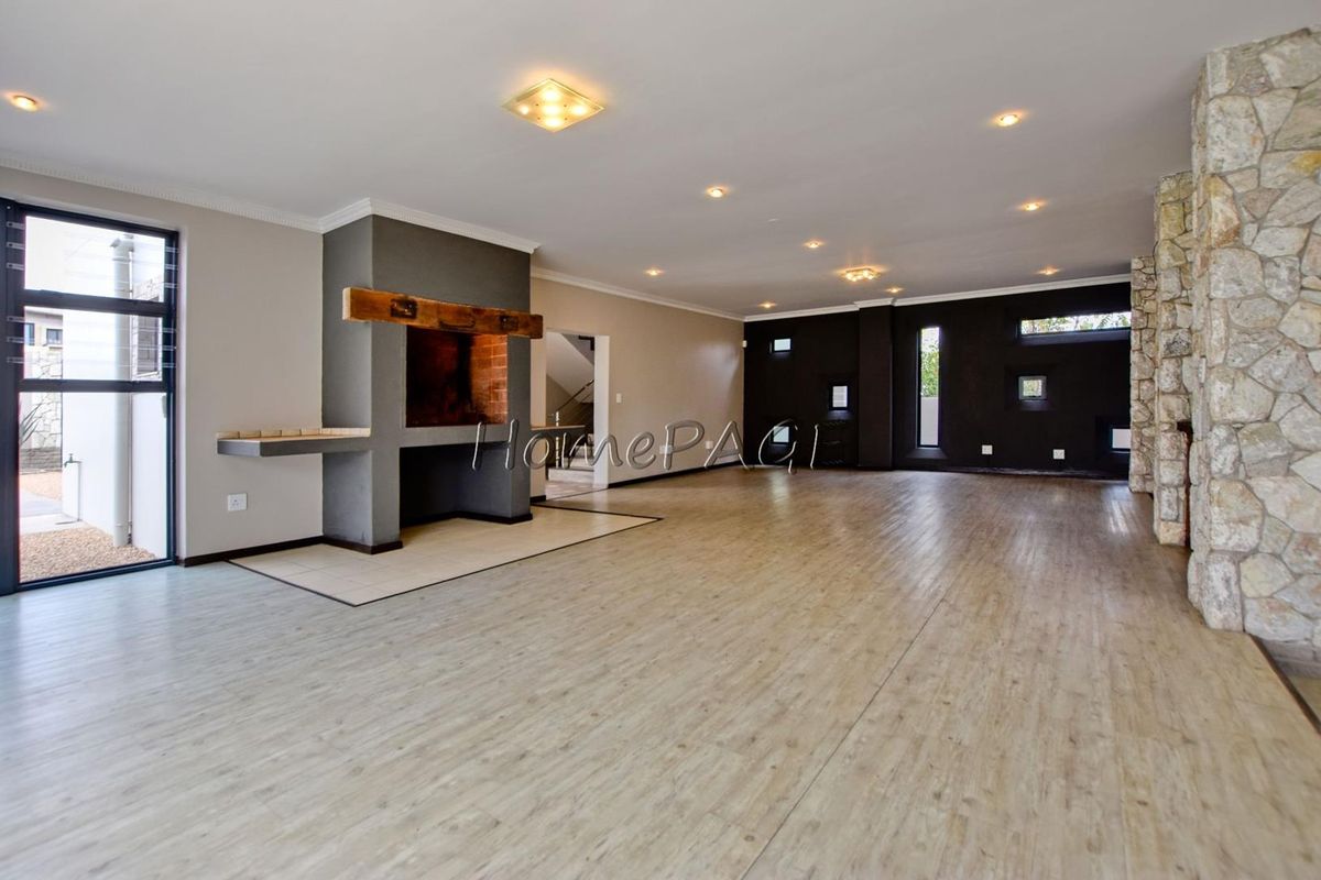 Spacious open-plan living area featuring a built-in fireplace, stone accent wall, and modern laminate flooring with recessed lighting throughout.