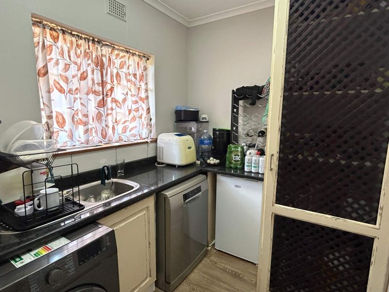 A functional scullery area featuring a stainless steel sink, granite countertops, and built-in cabinetry, providing convenient additional workspace and utility storage.