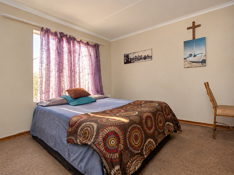A standard bedroom featuring carpeted flooring, a built-in wardrobe, and a window with natural light.